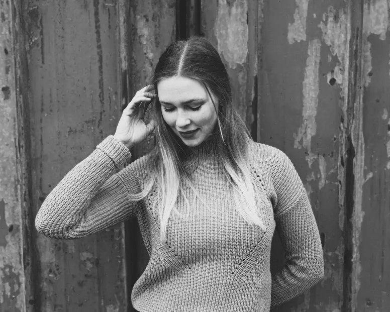 schwarz weiß portrait jungee blonde frau vor rustikaler wand